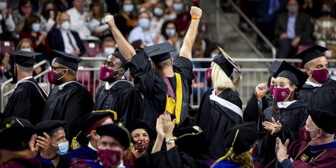 A student raising their hands in the air during a Commencement ceremony