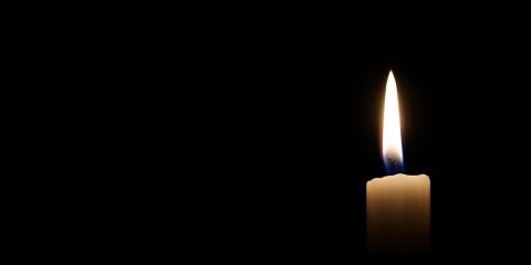 A lit candle against a black backdrop