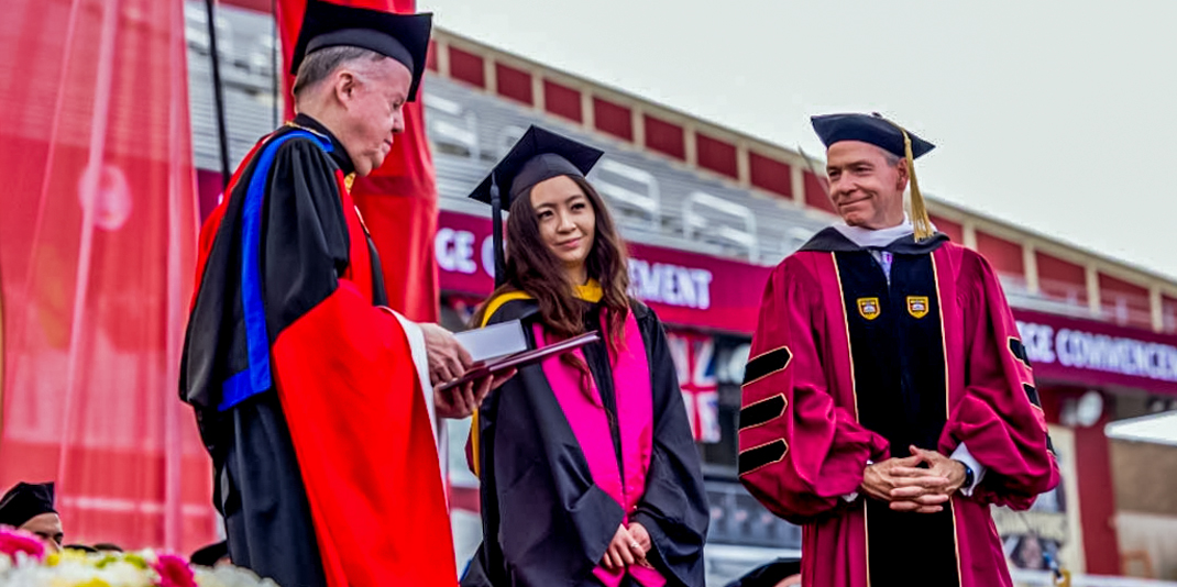 Jenna Mu in cap and gown receiving the Finnegan Award at Commencement