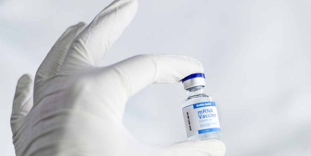 gloved hand holding vaccine serum bottle