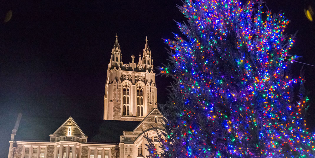 A lit Christmas tree in front of Gasson Hall