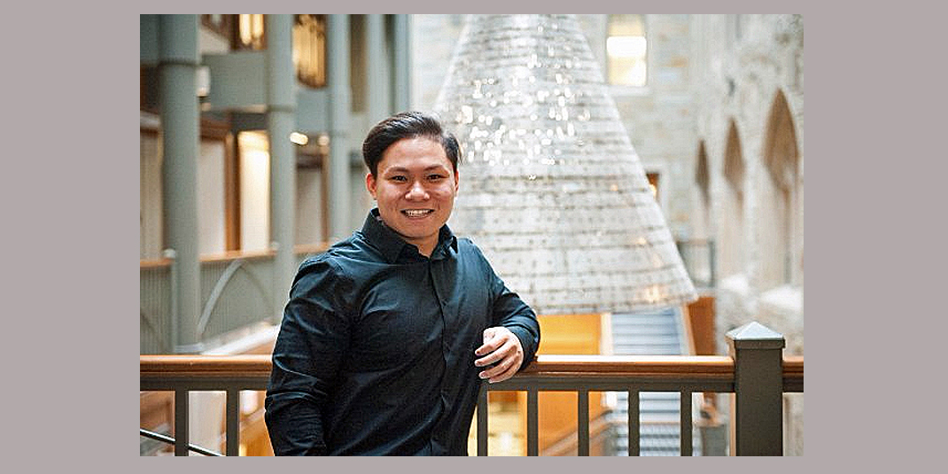  Phat Nguyen photographed in Fulton Atrium, leaning on a bannister