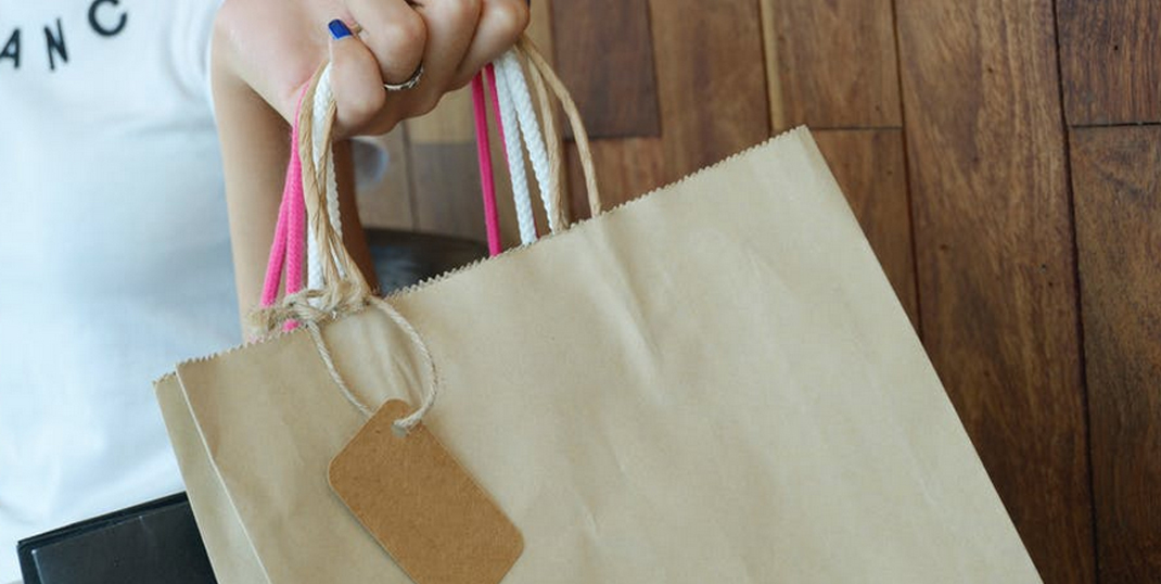 A hand holding paper shopping bags