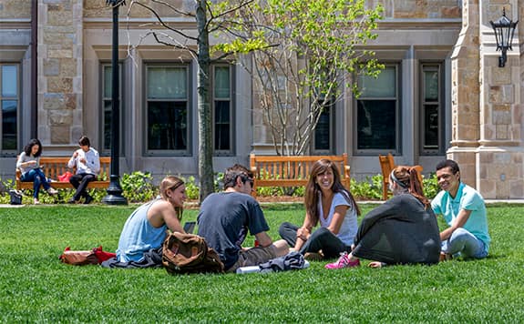 students sitting on the grass outside Stokes Hall looking happy