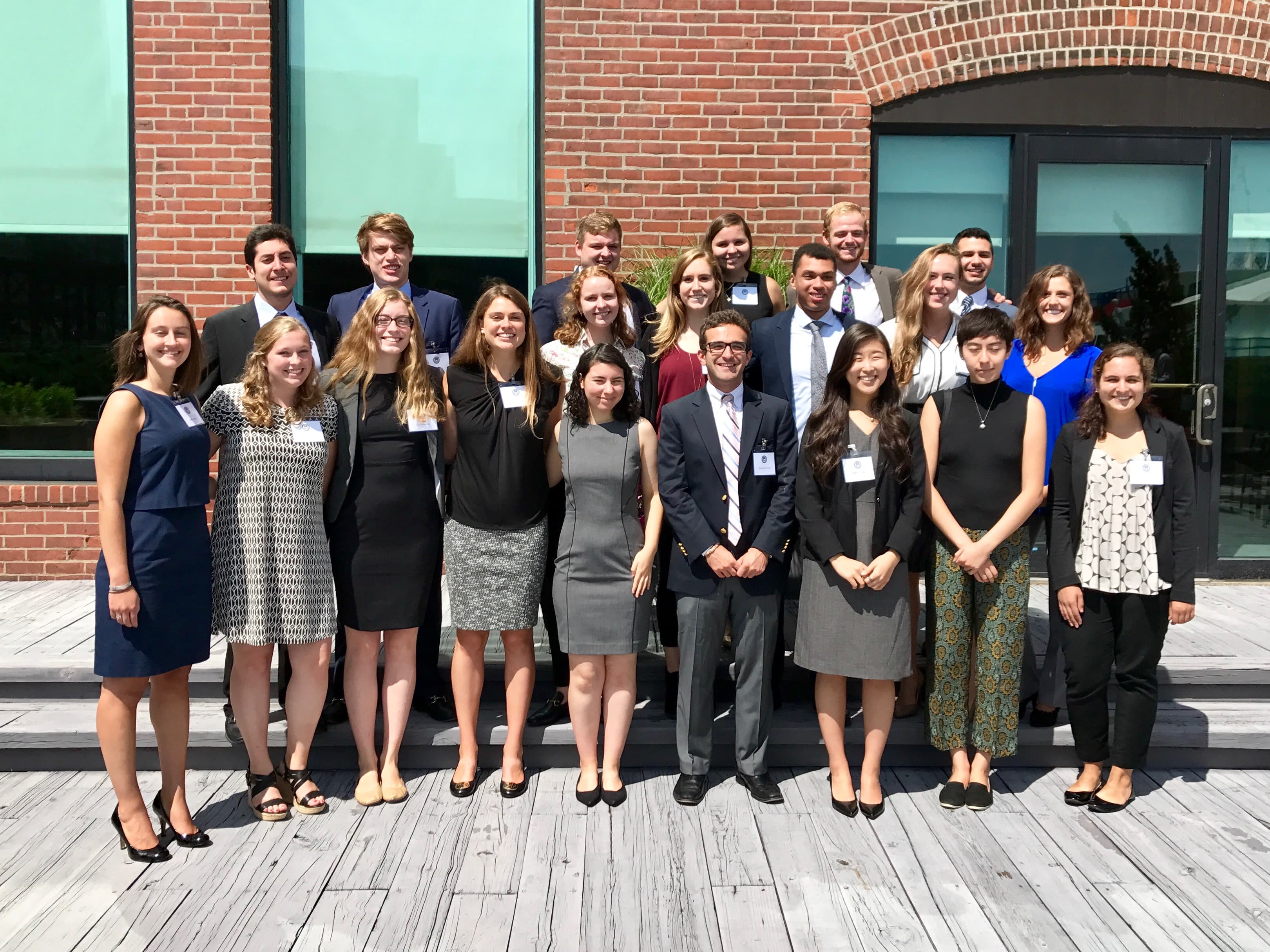 Group photo of interns in business casual clothes smiling outside of a building
