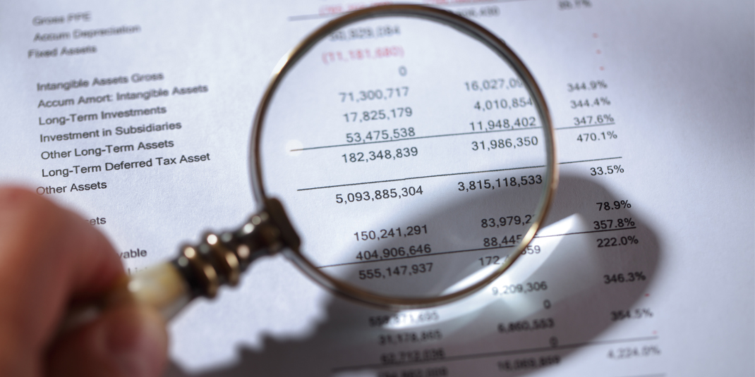 A balance sheet with a magnifying glass in front of it