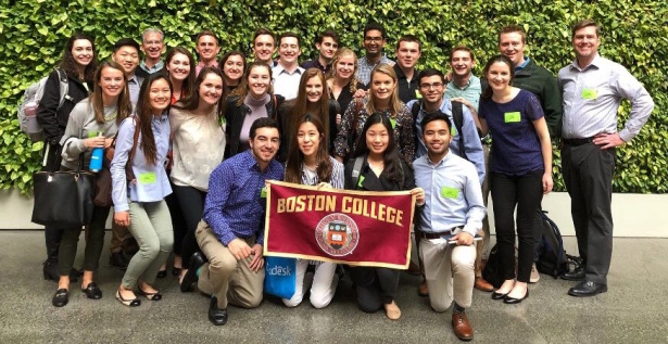 A group of students pose while holding a Boston College sign