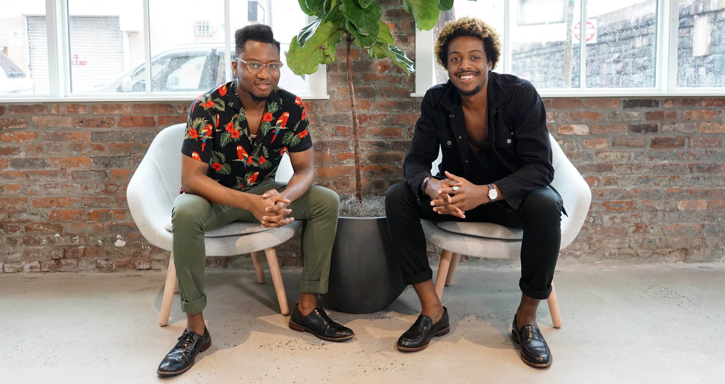 Ivan Alo and LaDante McMillon sitting in their office in front of a large plant