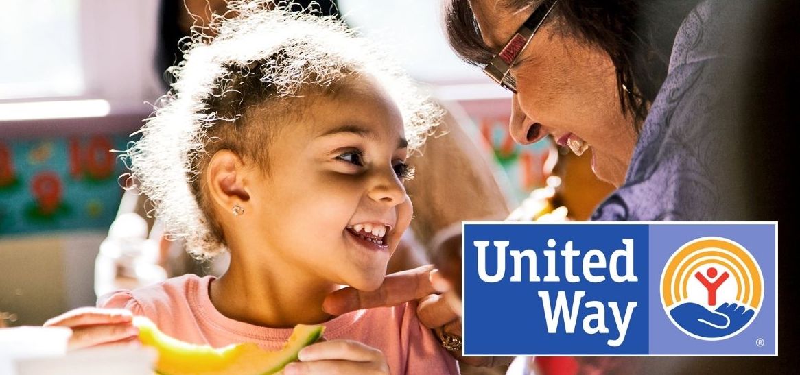 A young black girl smiles at an older black woman, United Way logo is in the lower right corner
