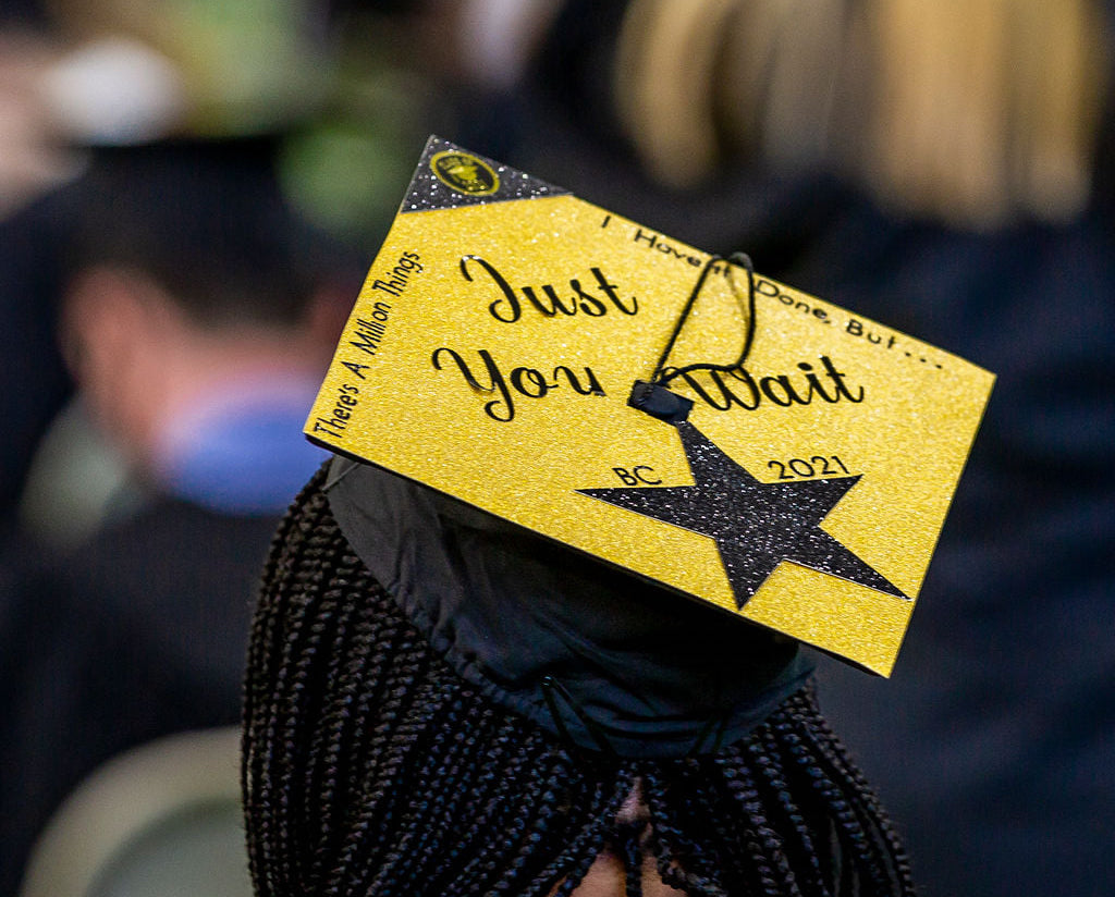 A graduation cap decorated with gold paper reading "Just You Wait" 