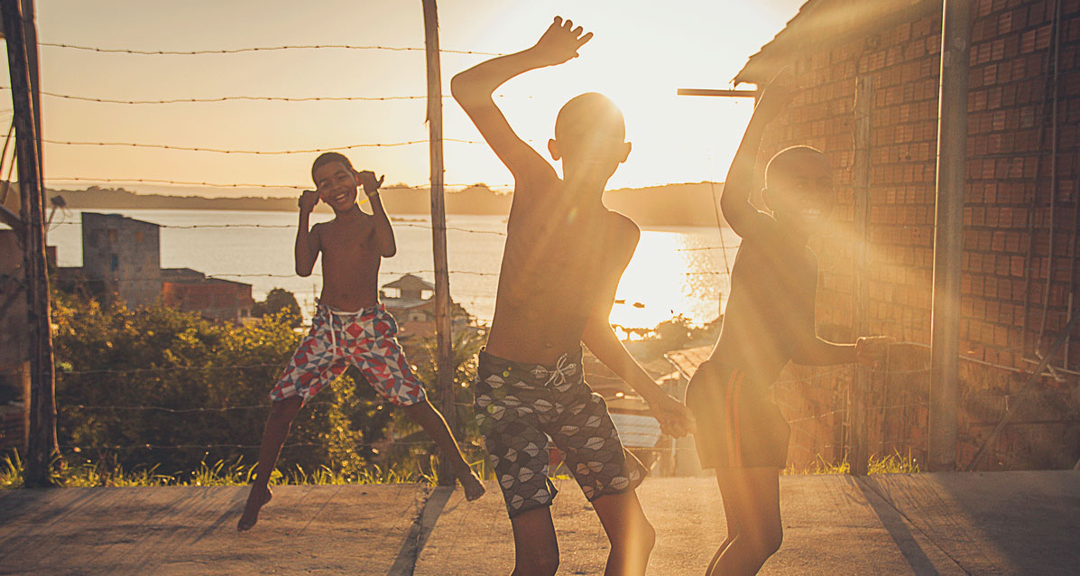 Three children in bathing suits playing while the sun sets