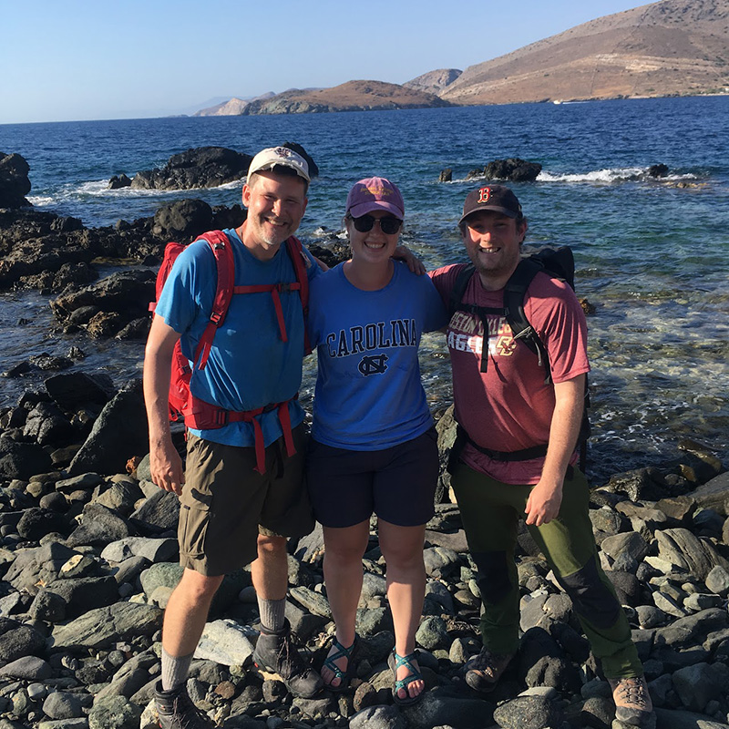 Three people in front of a body of water