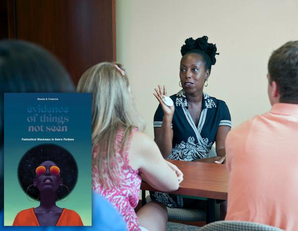 Professor Rhonda Frederick speaking with students with the cover of her book " Evidence of Things Not Seen: Fantastical Blackness in Genre Fiction" 
