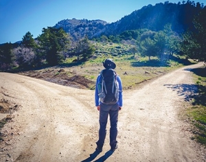 Hiker standing at a fork in a dirt road