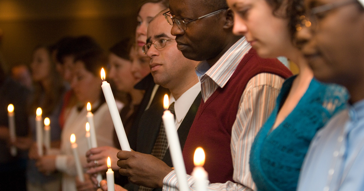 Diverse adults holding candles at a liturgy with thoughtful expressions