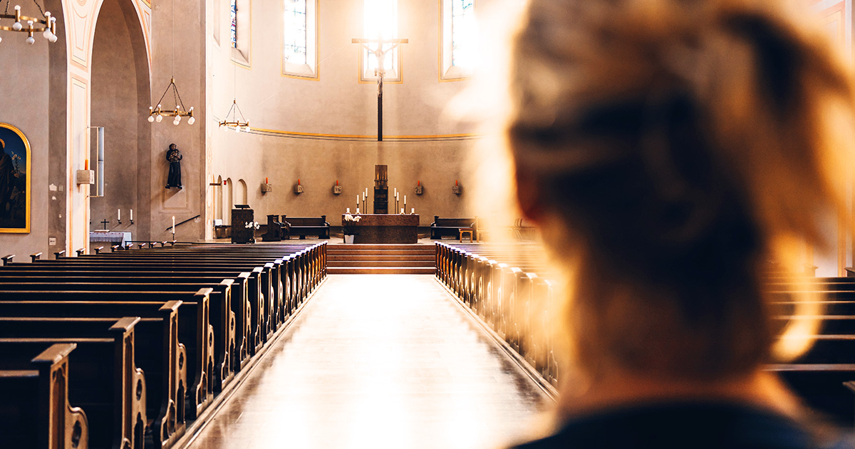 A woman looking towards the altar of an empty church
