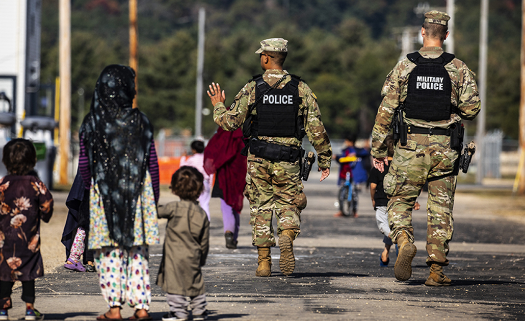 U.S. military police walk past Afghan refugees at the village at the Ft. McCoy Army base