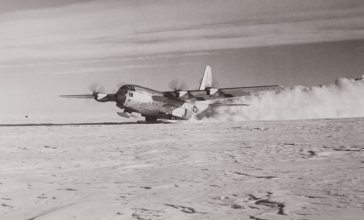 Tents and cargo on a snowfield with a plane in the background