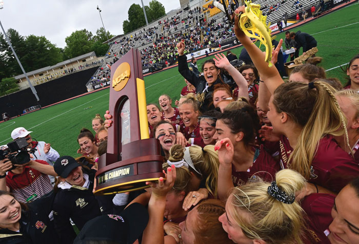 The women's lacrosse team hoisting the trophy in celebration