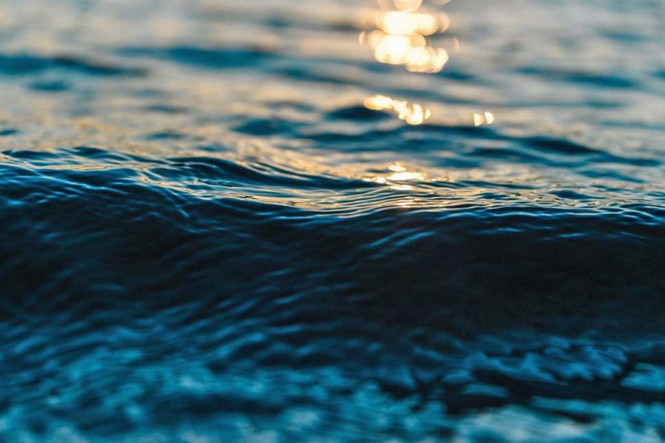 Wave of water with sun shining on surface