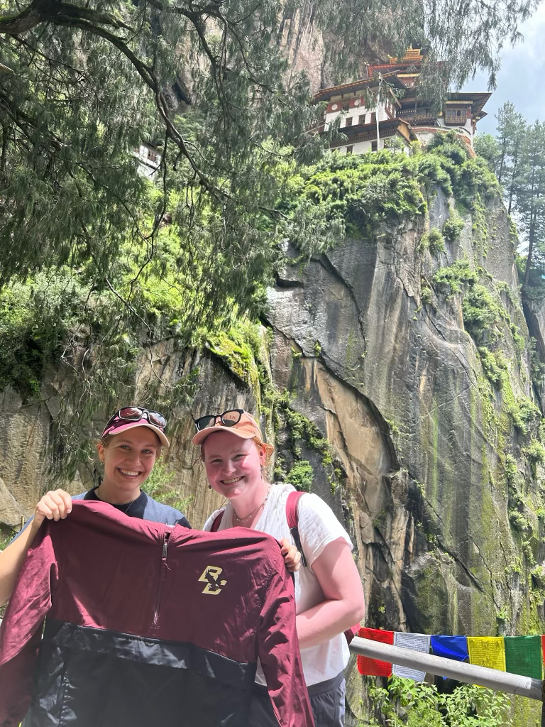 Two students holding a BC jacket near a temple
