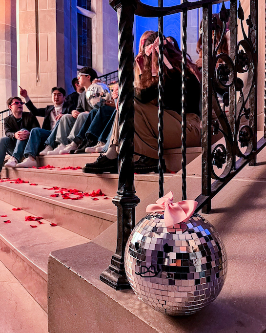 students singing on the stairs with a disco ball in the foreground