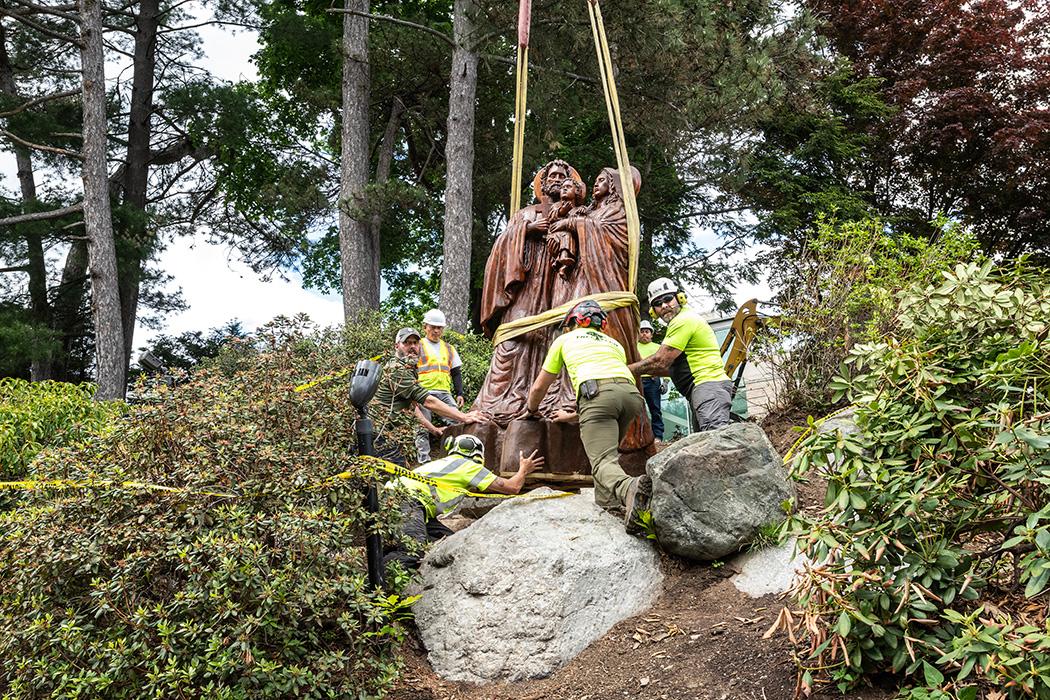 A crew lowering a statue onto a base