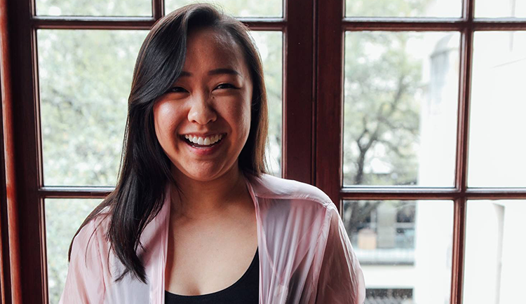 Angela Jin, '17, a young asian woman smiling in front of a window in Fulton Hall