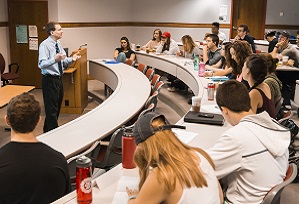 students sitting in a classroom as a professor animatedly lectures