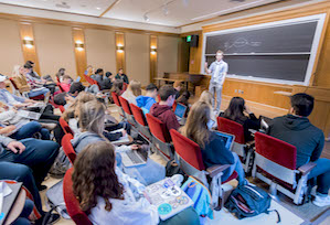 Harrison speaking to a full lecture hall of students